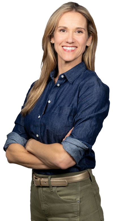 Smiling woman with arms crossed, wearing a blue denim shirt and olive green pants.
